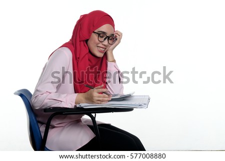A pretty muslim female student wearing hijab is studying isolated on white background