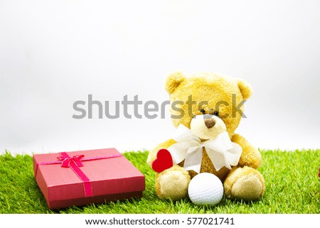 Bear with heart and golf ball on green grass. Gift for golfer on Valentine.