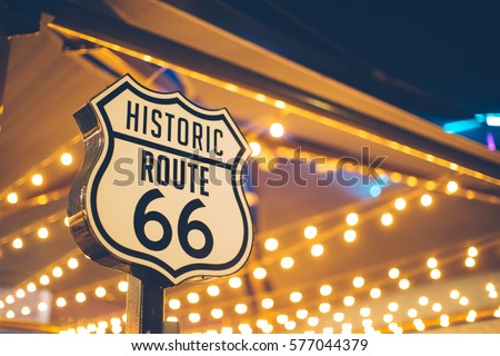 Historic Route 66 sign in California with decoration lights on the background Royalty-Free Stock Photo #577044379