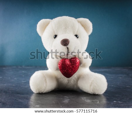 White teddy bear with love letter on red heart on gray background. Say i love you for valentine 's day concept.
