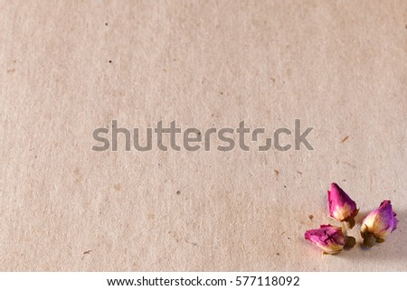 Cardboard background with dried rose buds in the corner