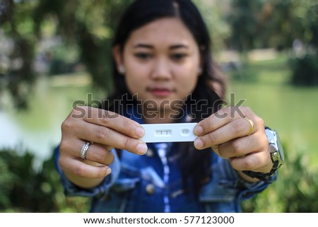 Woman wears jean jacket  holding test shows two adjacent black lines,test is positive and the woman is pregnant /test shows single line,it means test is negative, is not pregnant/Her different Emotion