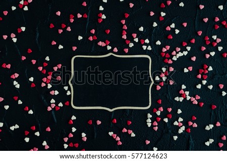 Lot of small different colors hearts on the dark stone background. Empty space for text or photo. Picture frame. Valentines backdrop. Valentine's Day theme.