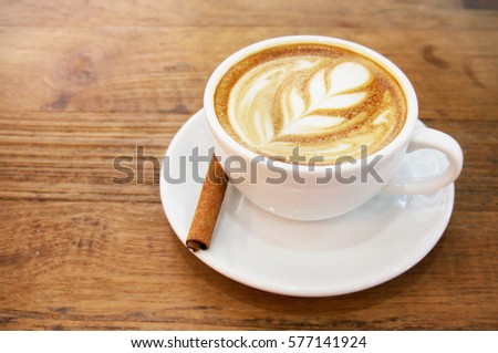 Cup of hot latte art with cinnamon coffee on wooden table  