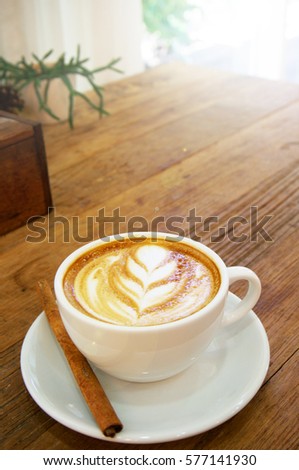 Cup of hot latte art with cinnamon coffee on wooden table  
