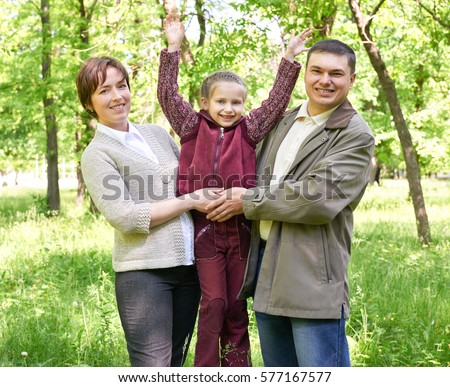 happy family with child in summer park, sunlight, green grass and trees