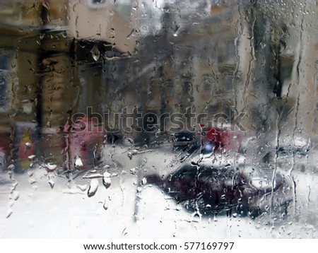 Abstract blurred winter city. Raindrops on a window. Silhouettes urban traffic.
