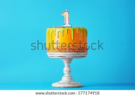 Birthday cake with one candle on blue background Royalty-Free Stock Photo #577174918