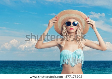 Attractive young woman in bikini and hat on a background of sea beach.