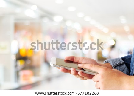 Hand using smart phone over blur store with bokeh light background, business and technology concept, digital marketing, seo, e commerce, lifestyle, social media network