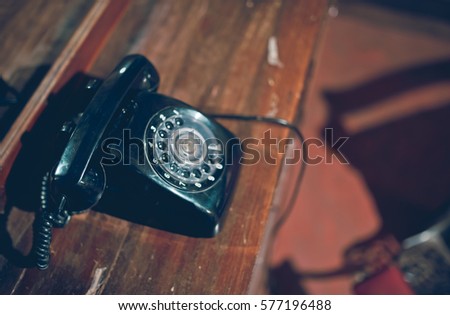 Retro grunge black telephone on wooden table in vintage style picture.