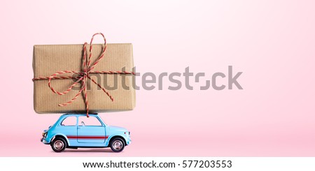 Blue retro toy car delivering gift box for Valentine's day on pink background Royalty-Free Stock Photo #577203553