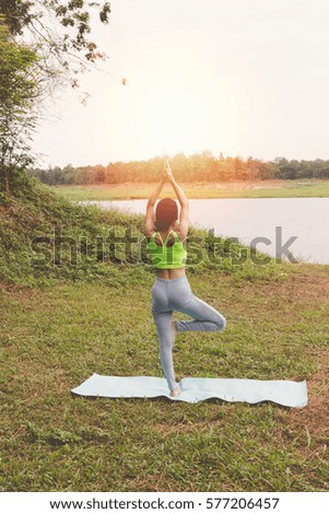 young girl practicing yoga exercises on mat outdoor in park. calmness and relax concept, woman happiness