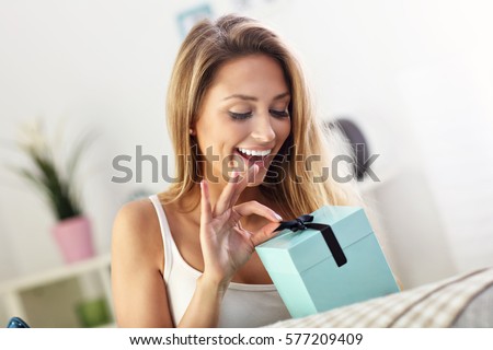 Picture showing woman opening present on sofa