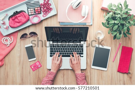 Fashion blogger working at office desk with a laptop: fashion, beauty and technology concept Royalty-Free Stock Photo #577210501