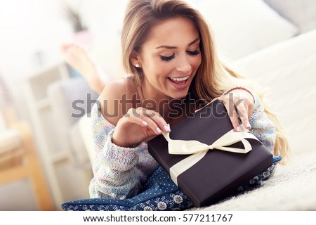 Picture showing woman opening present on carpet