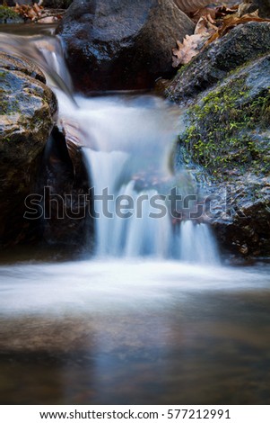 great wonders of stunning nature - close up of pure brook river waterfall flowing with rocks in winter scenery - long exposure