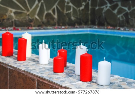 Candle float on water, Romantic evening with red and white candles and light bulb for couples in love or spa. Romantic mood. Valentine's Day. Pool with candles and rose petals floating on water