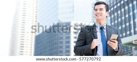 Young businessman using mobile phone while walking in the city - business travel and mobile roaming concepts, panoramic banner
