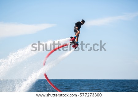 Silhouette of a fly board rider at sea Royalty-Free Stock Photo #577273300