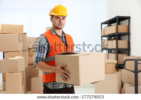 Handsome worker holding cartoon box at warehouse