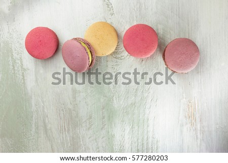 A photo of various macarons, shot from above on a teal background texture, with a place for text