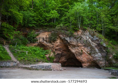 Natural cave in sandstone rock, former bank of Gauja river. Carved wall in Gutmanis cave in Sigulda, Latvia.