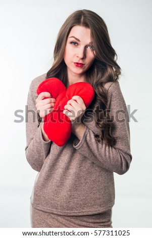 Studio shot of young attractive woman holding a red heart against white background