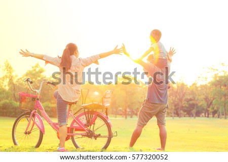 Silhouette of happy little girl child running into arms of his loving mother for hug with sun flare, in front sunset in the sky on Chatuchak Park at Bangkok City, Thailand. Concept of friendly family.