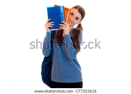 cutie young students girl with backpack and folders for notebooks in her hands looking at the camera and smiling isolated on white background