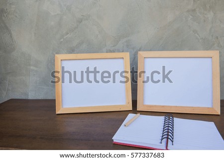 Two photo Frame on a wooden table and book on Gray wall background .