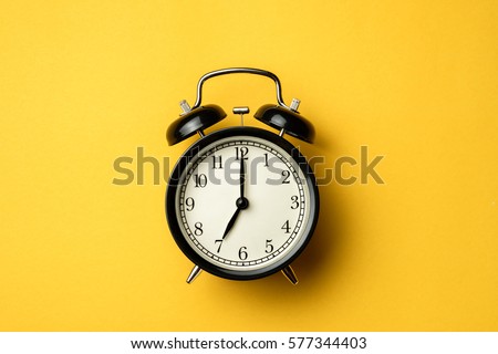 black vintage alarm clock on yellow color background Royalty-Free Stock Photo #577344403