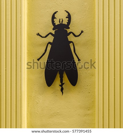 black metal beetle on a stylish yellow facade of the building