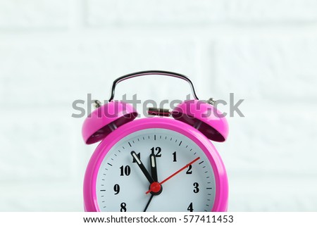 Pink alarm clock on the brick wall background
