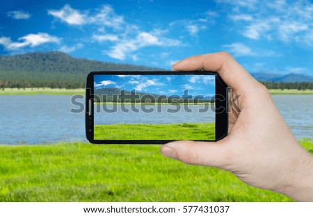 A man hand holding smart phone making photo on smartphone mobile closeup landscape view.