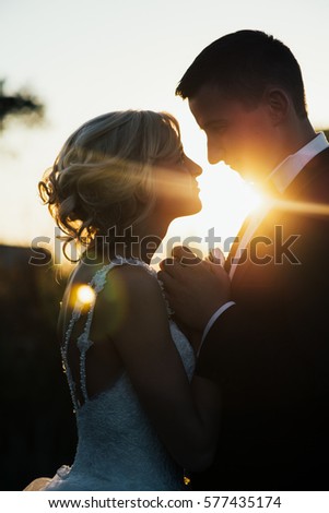 Gorgeous bride and groom looking each other against the sunset
