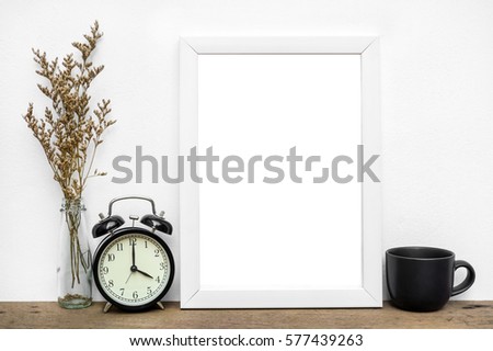 Blank white photo frame and flower on wooden table