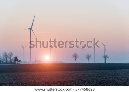 Beautiful sunset above the windmill on the field