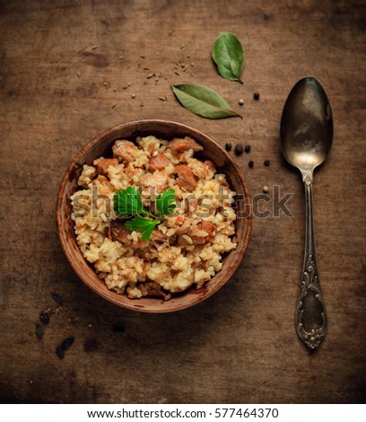 Fresh homemade pilaf - a Middle Eastern or Indian dish of rice cooked in stock with spices,  meat, onion and carrot in vintage wooden bowl on a rustic wooden background.  top view