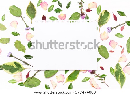 a sheet of paper for text in a frame of flowers, petals and green leaves on a white background.Inspirational image.Type flat, top view.