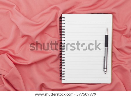 Blank paper notebook with pen on beautiful pastel silk background