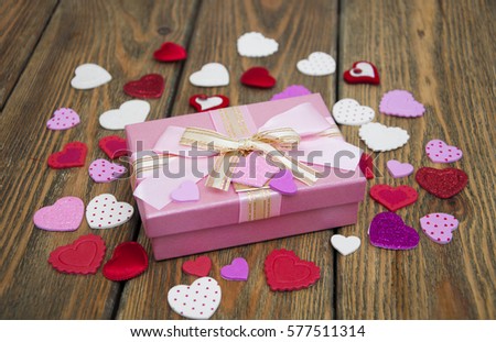 Valentines Day gift and small hearts on a wooden background