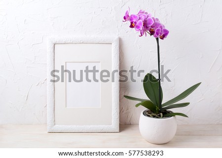 White frame mockup with purple orchid in flower pot. Empty frame mock up for presentation design.