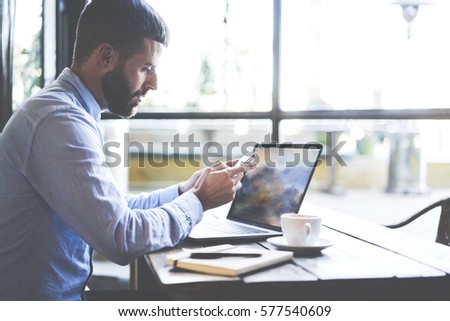 Experienced handsome male editor calling to chatting with journalists giving task for day while waiting for online translation of event drinking coffee in personal cabinet with free wireless network