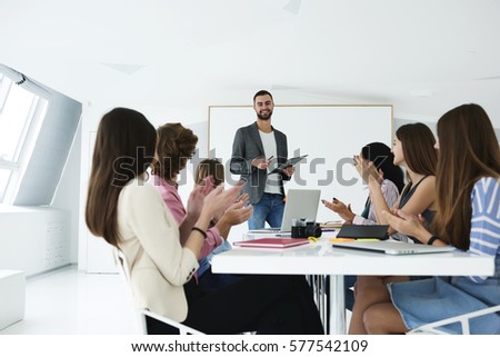 Handsome male business coach making training lecture about marketing strategy of advertising for group of skilled students using modern technologies and free wireless connection in coworking space