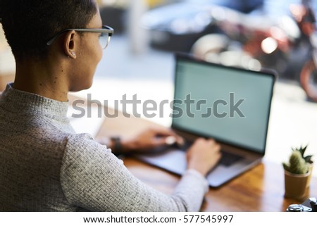 Young female international student  keyboarding on laptop computer while chatting with best friends in social network spending time in university campus using free wireless connection to internet 