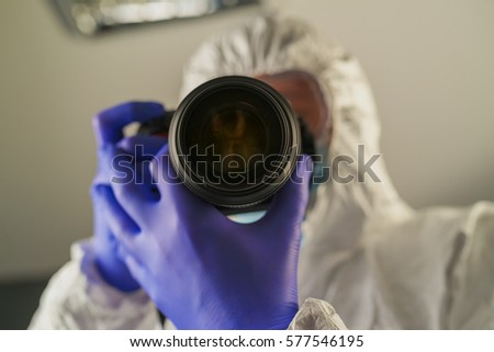 Crime scene forensics investigator with digital camera taking pictures as evidence for the investigation