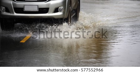 Motion car rain big puddle of water spray from the wheels through flood water after hard rain.Stop action ( capture with the high speed shutter) and selective focus,color toned. Royalty-Free Stock Photo #577552966