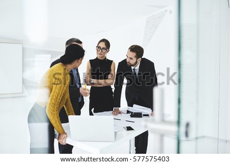 Crew of skilled marketing experts consulting with executive about rebranding of corporation suggesting new advertising campaign to change style sharing opinions on formal meeting in conference hall Royalty-Free Stock Photo #577575403
