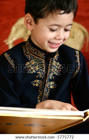 Beautiful young boy in traditional Indian clothing enjoying his storybook in a home environment.
